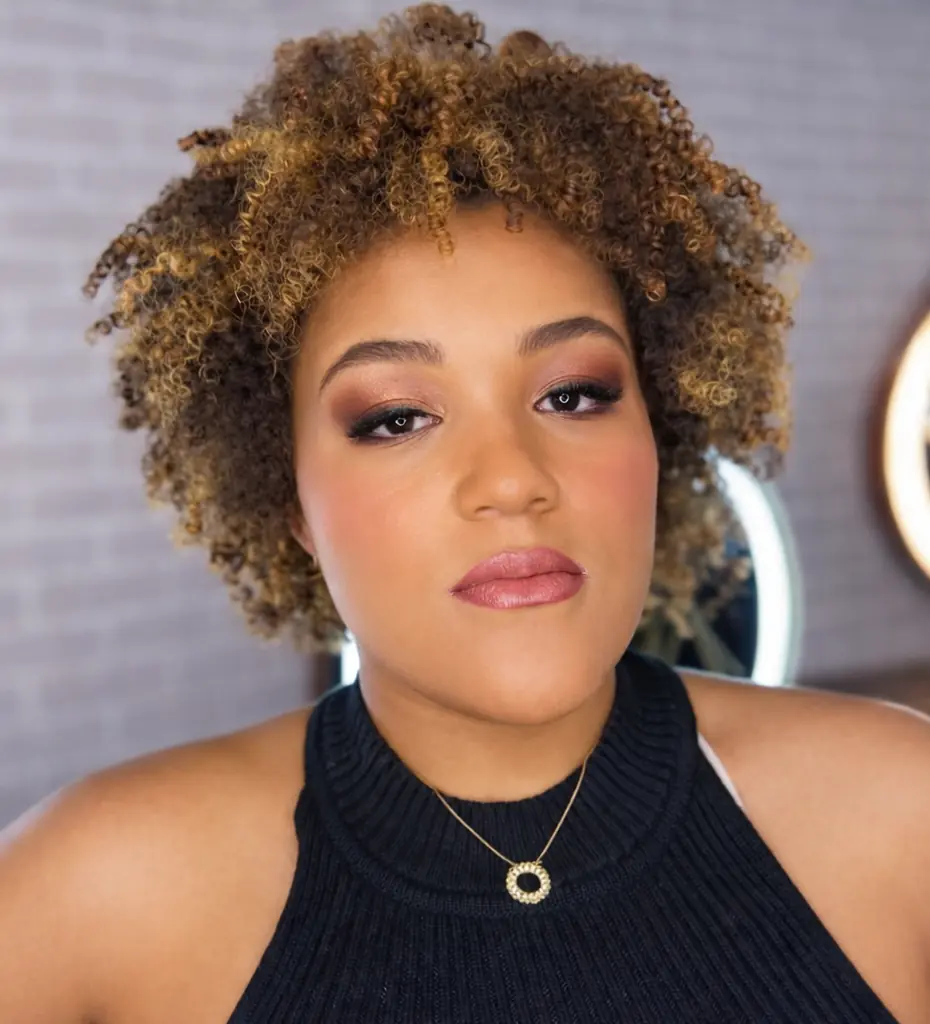 Mulher com cabelo cacheado curto e mechas após corte com visagismo em Moema